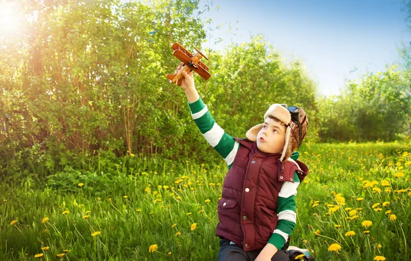 Boy playing in aviator hat with old plane — Stock Photo, Image