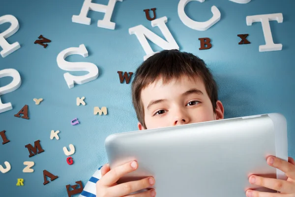 Yedi yaşında çocuk Tablet ve harfler ile yalan — Stok fotoğraf