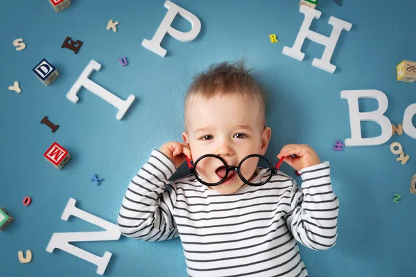 Einjähriges Kind liegt mit Brille und Buchstaben — Stockfoto