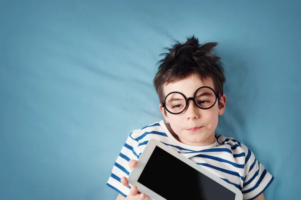 Enfant de sept ans couché avec une tablette — Photo