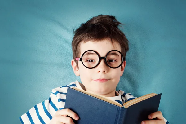 Sju år gammal barn liggande med bok — Stockfoto