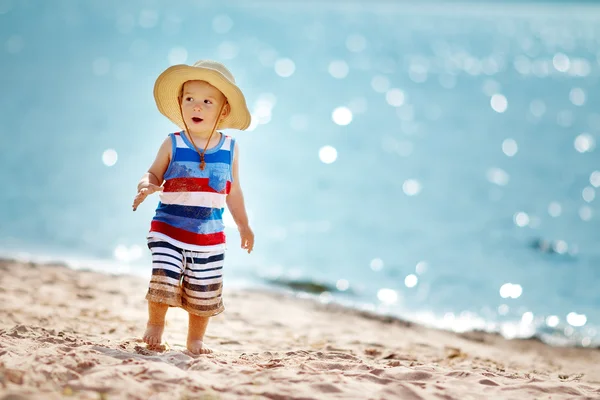 Wandelen op het strand in stro hoed jongetje — Stockfoto