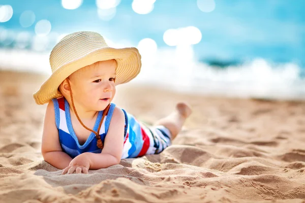 Liten pojke liggande stranden i stråhatt — Stockfoto