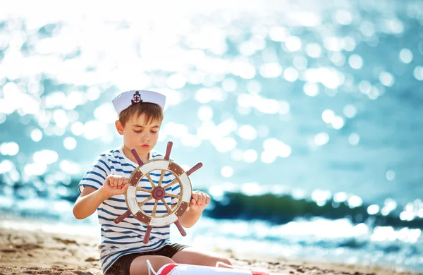 Мальчик играет на пляже с рулем — стоковое фото