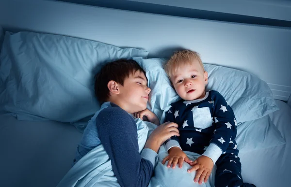 Children lying in bed at night — Stock Photo, Image