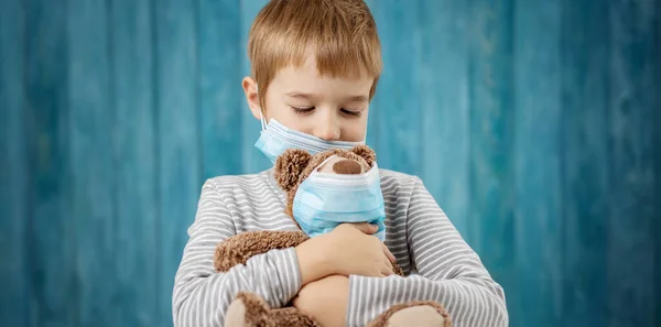 वैद्यकीय चेहर्यावरील मुखवटात टेडी अस्वल असलेला लहान मुलगा — स्टॉक फोटो, इमेज