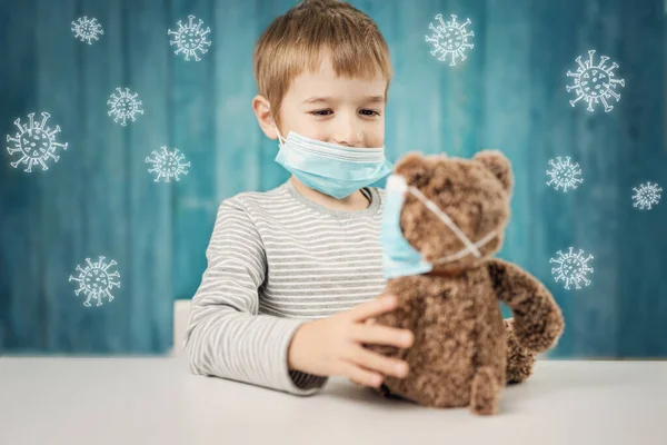 Petit garçon assis à la table avec un ours en peluche dans des masques médicaux — Photo