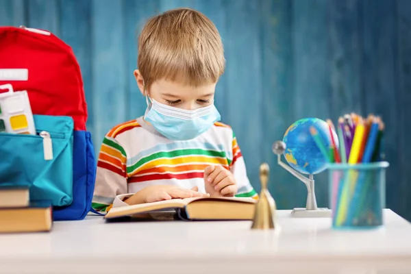 Хлопчик в медичній масці для захисту обличчя в приміщенні на синьому фоні — стокове фото