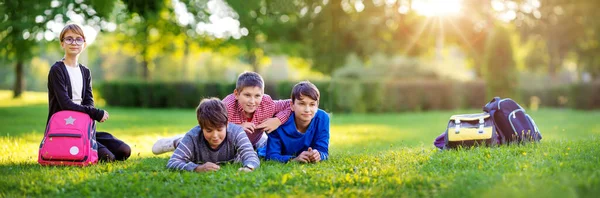 Niños con mochilas de pie en el parque cerca de la escuela —  Fotos de Stock