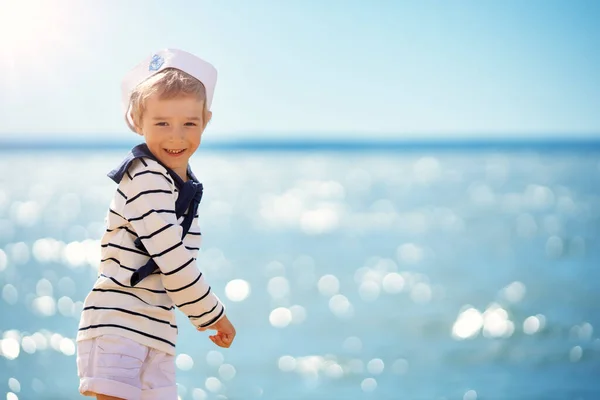 Słodki chłopiec w czapce marynarza stojący na brzegu morza morza — Zdjęcie stockowe