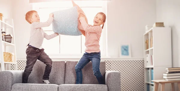 Leuke kinderen vechten door kussens op de bank — Stockfoto