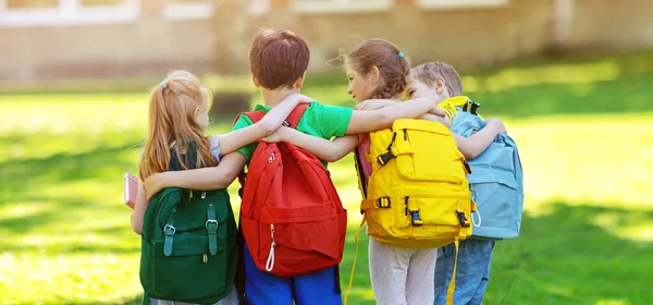 Group of children with rucksacks standing in the park near the school — Stock Photo, Image