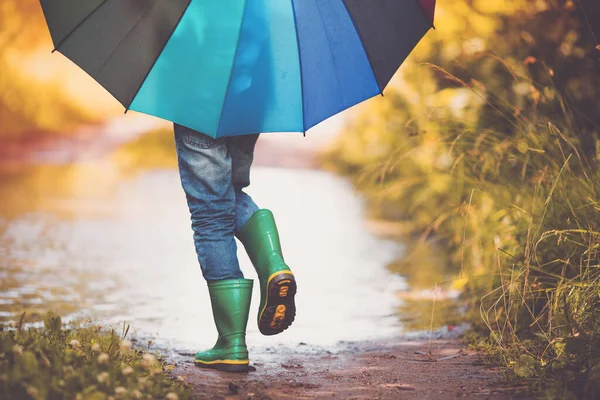 Kind läuft bei Regenwetter in Gummistiefeln in Pfütze — Stockfoto