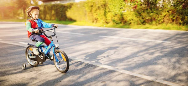 Boldog fiú a biciklin az úton a városban. — Stock Fotó