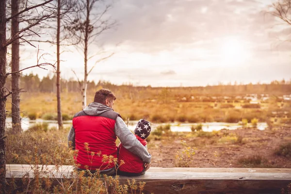 Father with son sitting on the bench on the Estonian bogs. — Stock Photo, Image