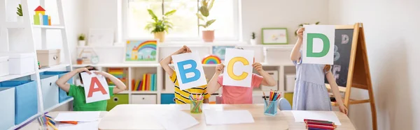 Gyerekek ülnek az osztályteremben, és megmutatják a betűket.. — Stock Fotó