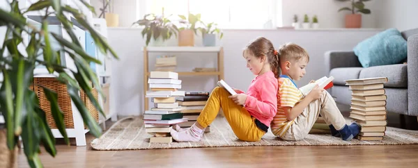 Dos niños sentados en el suelo en la habitación y leyendo libros —  Fotos de Stock