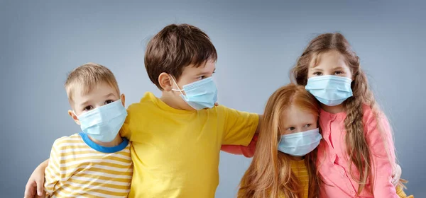 屋内に立つ医療用マスクの4人の子供のグループ. — ストック写真