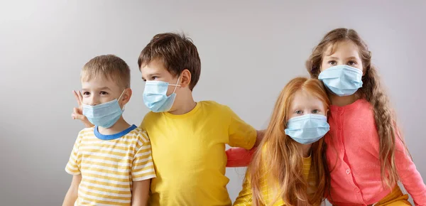 Kelompok dari empat anak dalam topeng medis berdiri di dalam ruangan. — Stok Foto