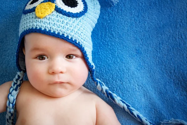 Small baby in owl hat on blue background — Stock Photo, Image