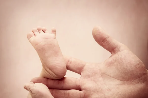 Baby voeten in mans hand — Stockfoto