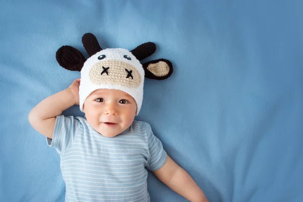 Baby in een hoed koe op blauwe deken — Stockfoto