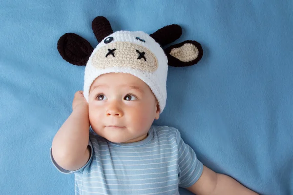 Baby in a cow hat on blue blanket — Stock Photo, Image