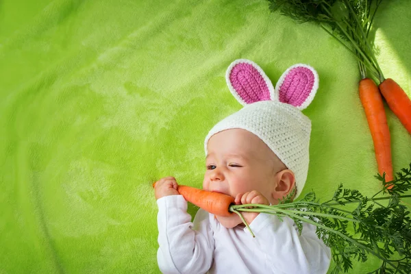 Baby in rabbit hat eating carrot — Stock Photo, Image