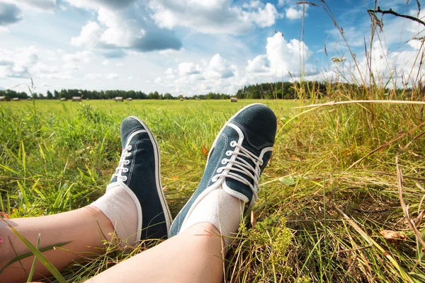 Füße auf Feld mit schönen Wolken — Stockfoto
