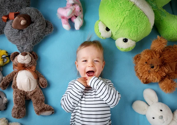 Feliz niño de un año acostado con muchos juguetes de peluche —  Fotos de Stock