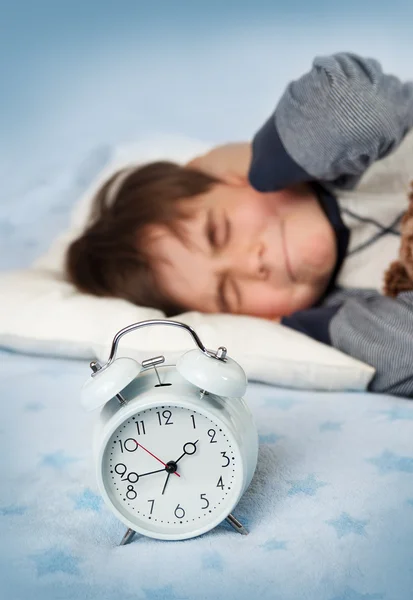 Шесть лет ребенок спит в постели с будильником — стоковое фото