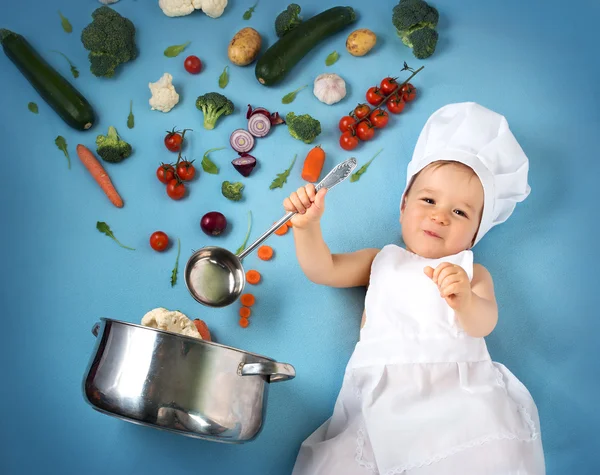 Niño en sombrero de chef con sartén y verduras — Foto de Stock