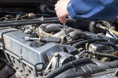 Screwing on a vintage car, master craftsman screwing on an engine with a ratchet, hand and bluesuit, close-up.