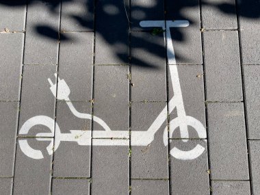Bir sokak manzarası. Elektrikli scooter şarj istasyonu, sokaktaki sembol..