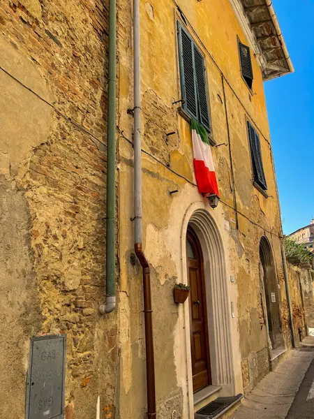 Reális nézet az olasz zászlóról. A zászló kilóg az ablakon. Óváros Olaszországban. — Stock Fotó