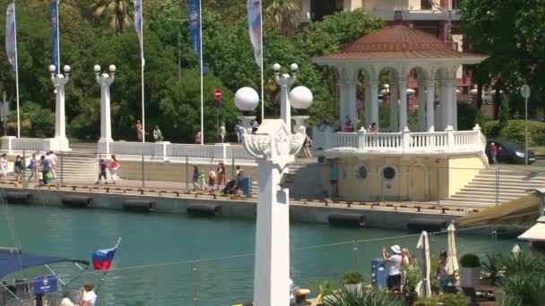 La gente camina en la rotonda en el puerto. — Vídeos de Stock