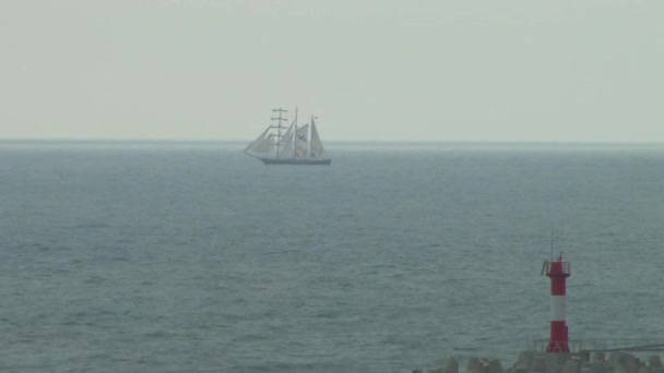 Zeilschip op een achtergrond van een vuurtoren in een stormachtige zee — Stockvideo