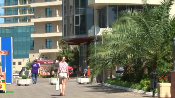 As pessoas caminham ao longo do passeio à beira-mar — Vídeo de Stock