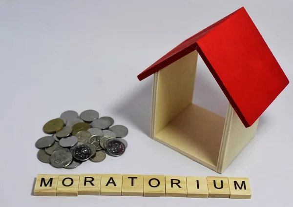 Moratorium kelimesi küçük ahşap harflerle ve minyatür bir evin altında ve bir sürü bozuk para kullanarak heceleniyor.