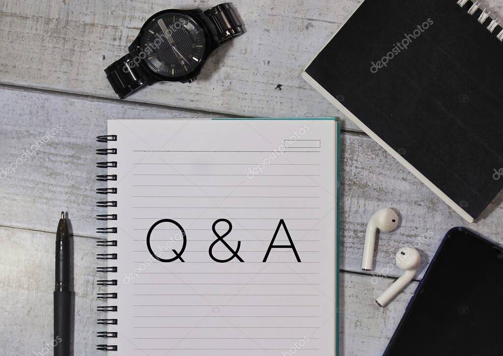 Top view of pen, watch, wireless earphones, smartphone and notepad with text Q and A.
