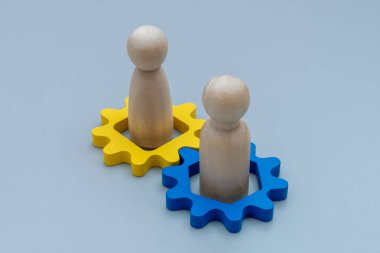 İki tahta insan figürü ve ahşap teçhizat. Takım çalışması, işbirliği, işbirliği, ortaklık, liderlik ve birlikte çalışma kavramı.