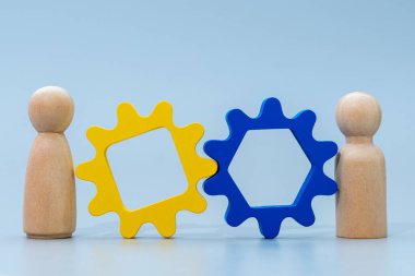 İki tahta insan figürü ve ahşap teçhizat. Takım çalışması, işbirliği, işbirliği, ortaklık, liderlik ve birlikte çalışma kavramı.