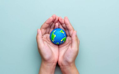 Küçük bir Dünya modelini tutan bir el. Küresel koruma, çevresel bakım, sürdürülebilirlik kavramı. Metin için alanı kopyala.