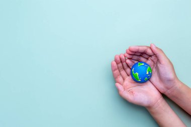 Küçük bir Dünya modelini tutan bir el. Küresel koruma, çevresel bakım, sürdürülebilirlik kavramı. Metin için alanı kopyala.