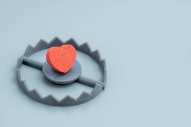 Bir kırmızı kalp ayı kapanının içine yerleştirilir. İhanet, kalp kırıklığı, ilişki riski, aşk tuzağı, zehirli ilişkiler konsepti.