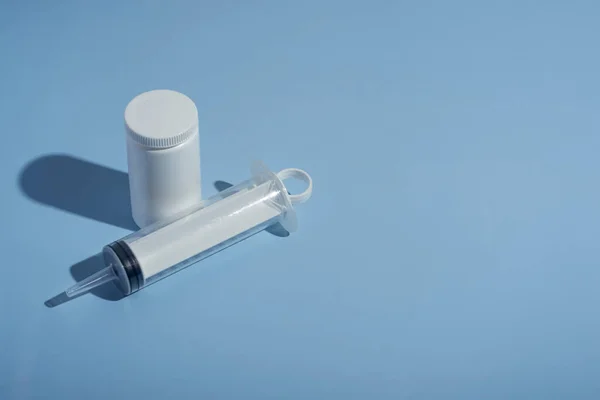Pills, syringe for a catheter on a blue medical background. close-up, top view. Medical syringe, tube with vitamins