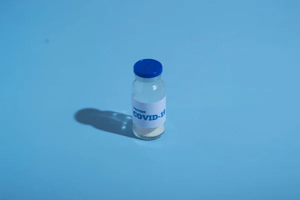 Bir ampul covid-19 aşısı. Coronavirus tedavisi, salgın kontrol. Mavi arkaplan, kopyalama alanı. Aşı konsepti. İlaç.