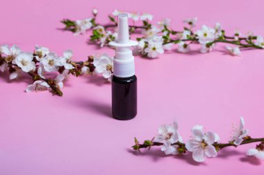 Burun için aerosol. Pembe arka planda aerosol kutusu. Yerleşim planı. Çiçekli dal. Alerji