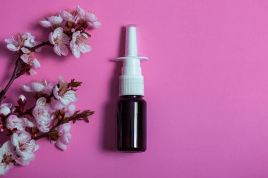 Burun spreyi ve pembe arka planda çiçek açan dal örneği. Alerji ilacı.