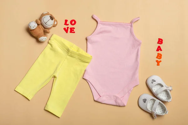 Pembe bebek gömleği, sarı pantolon, renkli arka planda oyuncakları olan beyaz ayakkabılar. Logoların ve reklamların dizayn ve yerleştirilme planı.